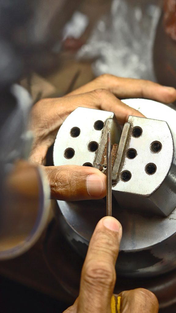 Hand setting a round diamond into a ring prong