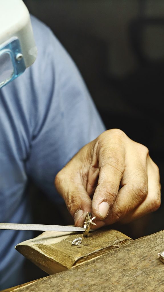 Craftsman setting diamond into gold ring