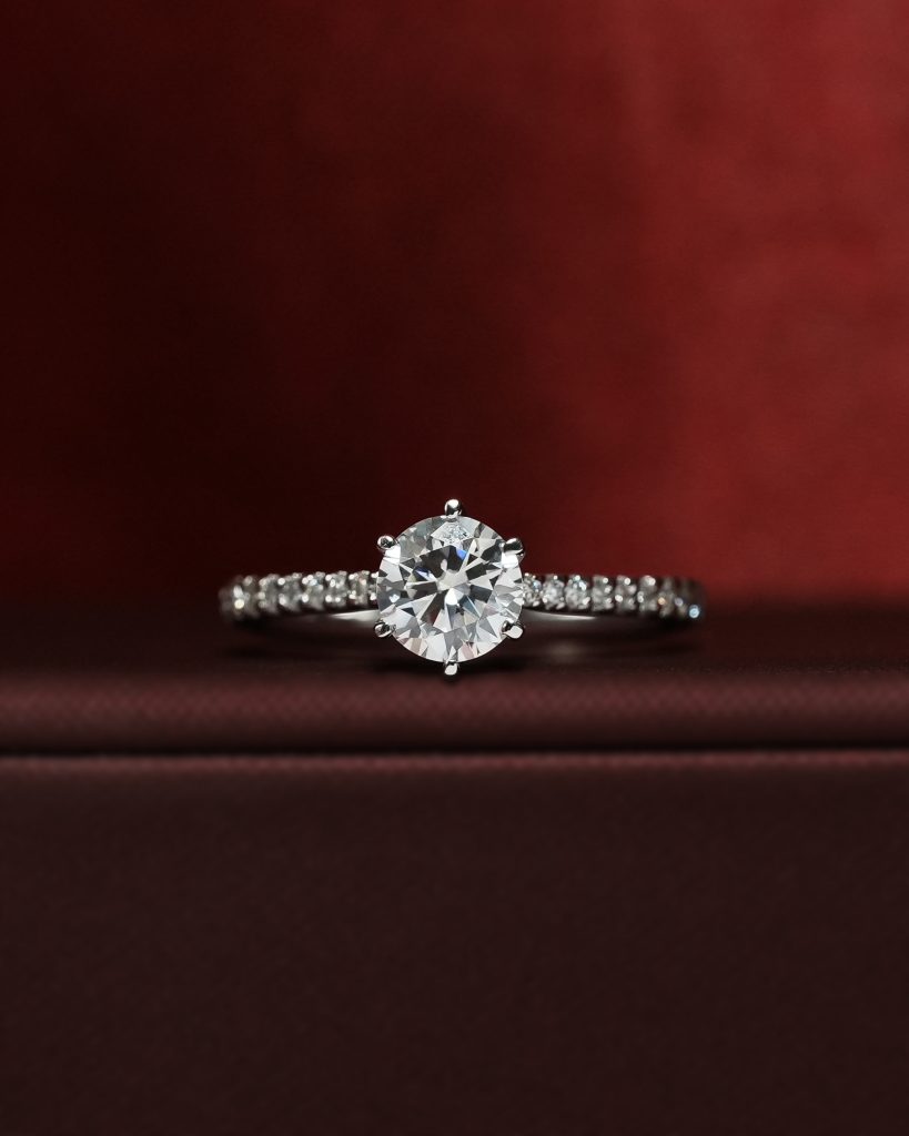 Round cut diamond ring on red background